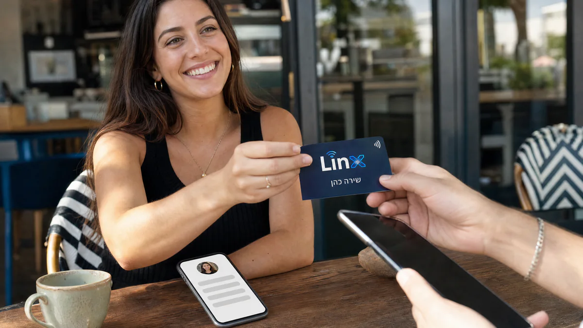 מסירת כרטיס NFC של LINX בבית קפה, לצד עמוד הקישורים הפתוח בנייד